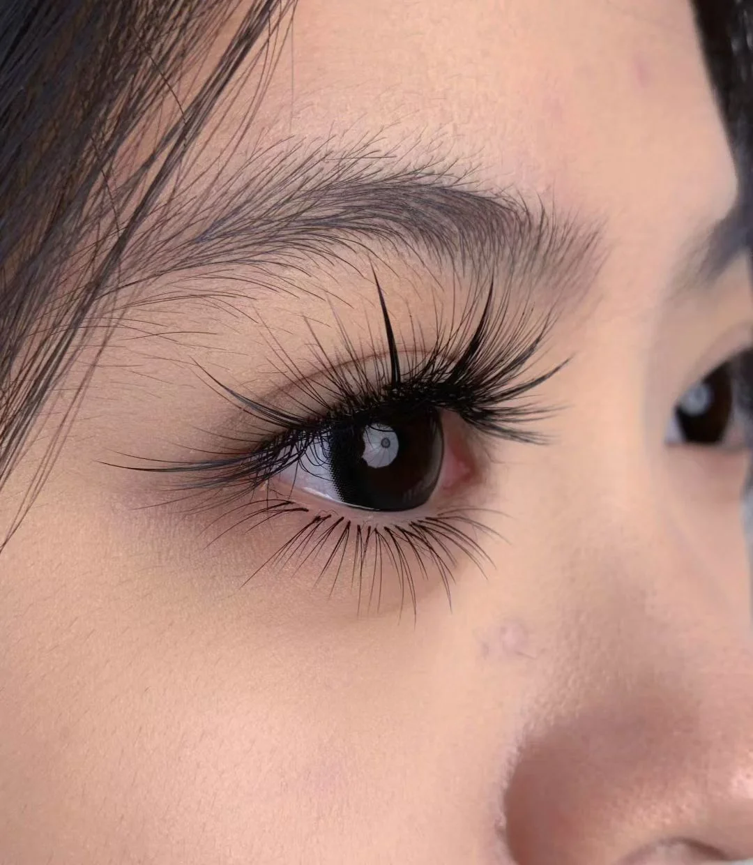 Close-up of a finished lash extension set at yeux by qun — dramatic feathered black lashes framing a single eye, mapped to the natural eye shape