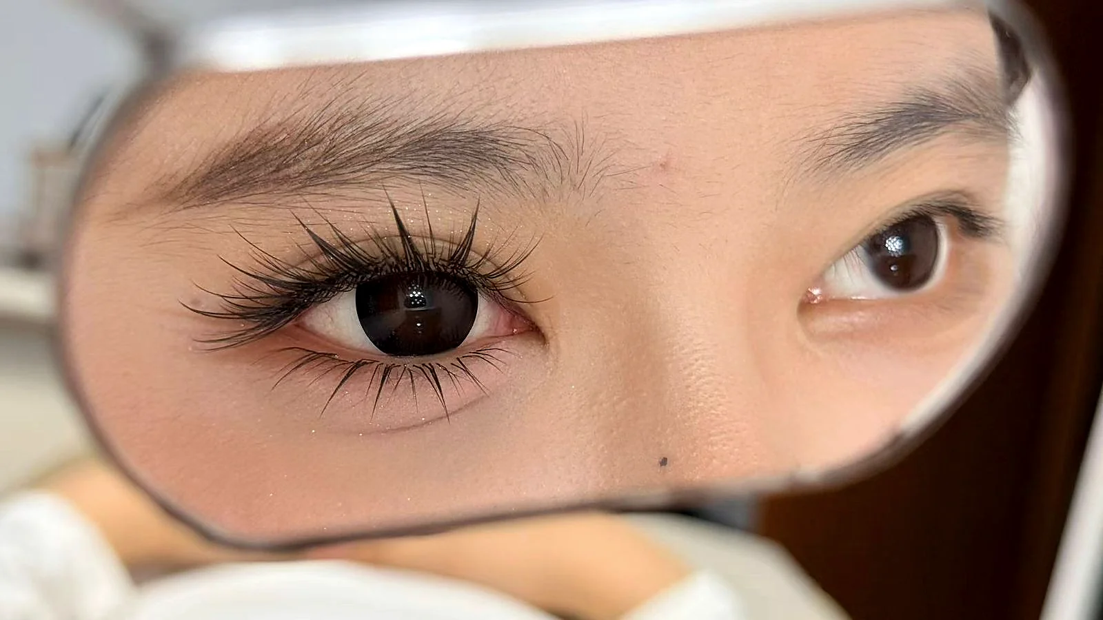 Reflected view of a finished Zero-Sensation Ultra-Lock lash set — feathered velvet curl with the iris visible underneath