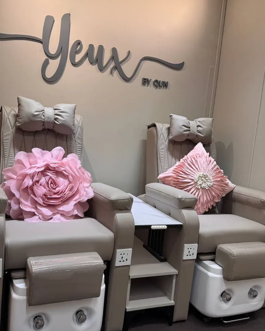 The yeux by qun nail studio in Hougang: two pedicure chairs with pink flower cushions beneath the Yeux by Qun wall sign